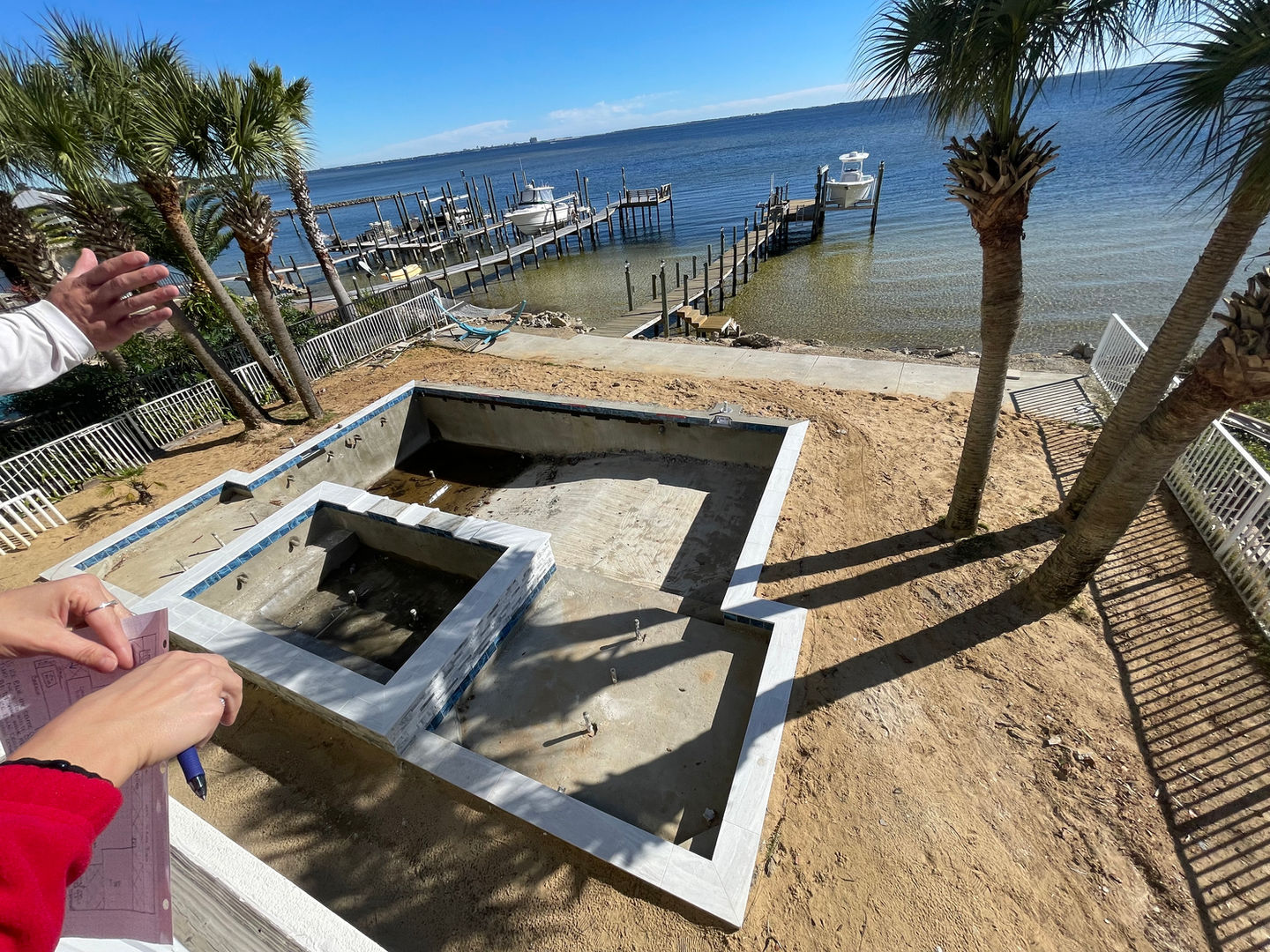 Luxury waterfront backyard with custom pool, artificial turf installation, gas fire pits, and modern outdoor living design by Turf Tailors in Fort Walton Beach, Florida. Destin pavers palm trees