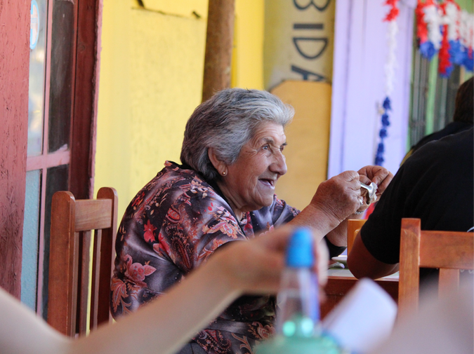 Smiling elderly woman enjoys a meal in Til Til, Chile