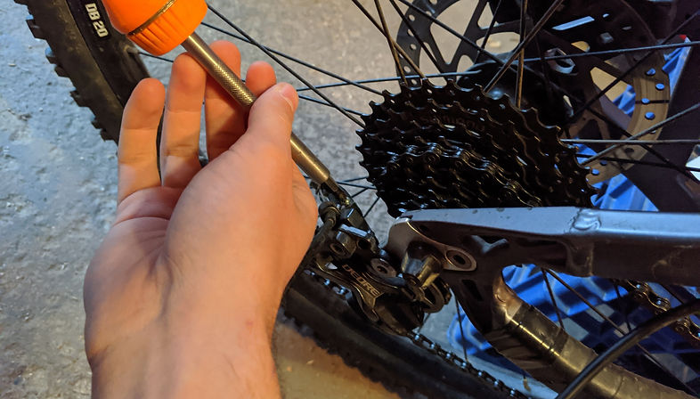 Brett adjusts a rea derailleur with an orange screwdriver