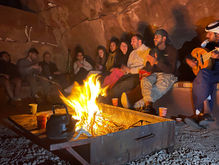 bedouin playing oud instrument for tourists sitting around the campfire in the wadi rum desert