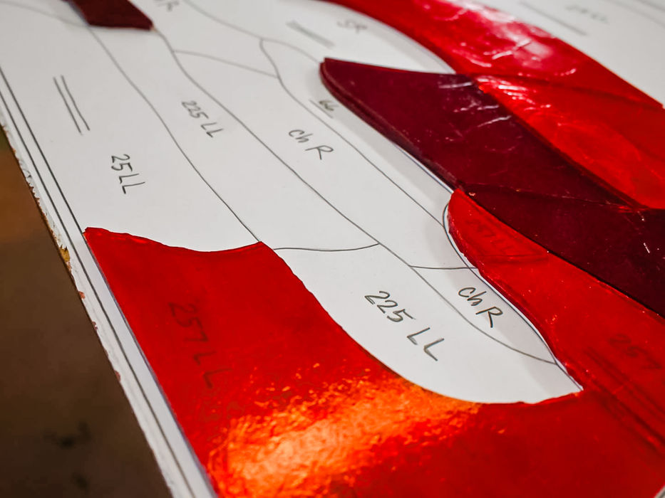 Red stained glass pieces on a pattern with markings
