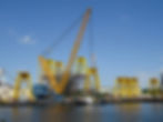 Large cranes lifting offshore wind Transition Pieces at port
