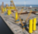 Large cranes lifting offshore wind heavy metal components at port
