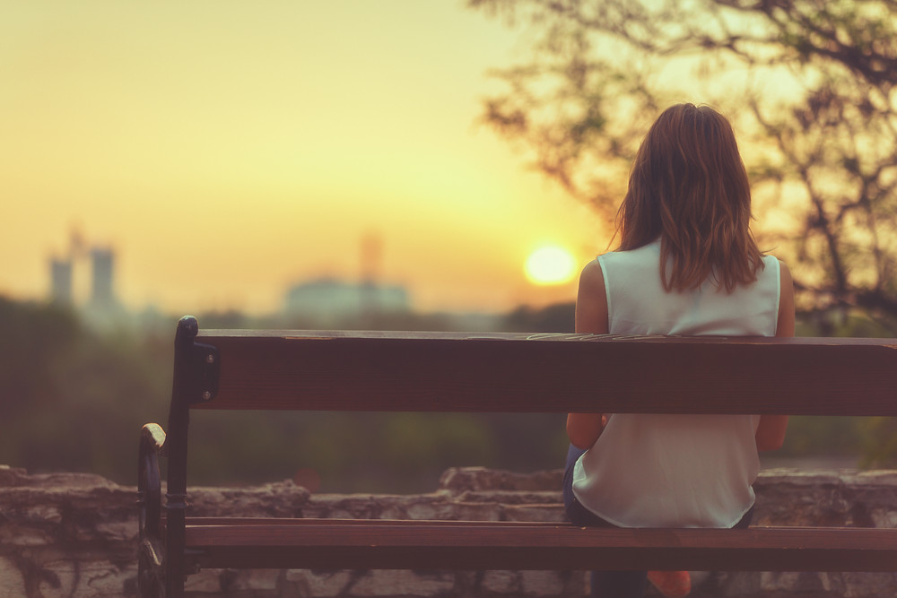 Woman Thinking about Ending her relationship sitting on a bench