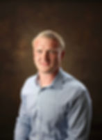 Portrait of Solomon Huffman, owner of Apex Builders NC, standing in front of a light background.