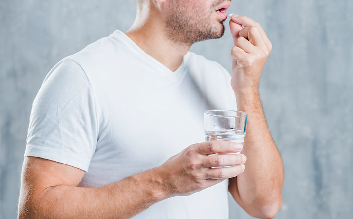 young-man-holding-glass-water-taking-med