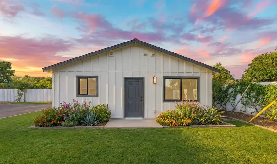 Exterior image of completed casita in backyard with farmhouse style board-and-batten siding and modern lighting in Phoenix