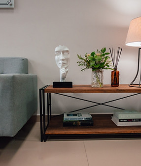 Sofá elegante e mesa de centro com escultura, flores e luminária