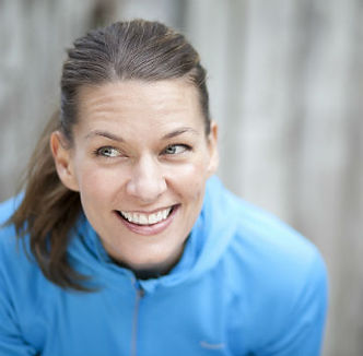 Headshot of a female trainer smiling, glancing sideways, leaning into camera.