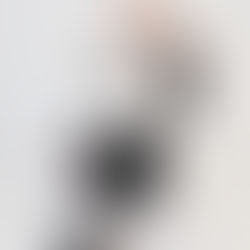 Person sitter på golvet i svart outfit med laptop framför sig och håller upp ett papper med texten 'Why Display Pricing?'. Runtom ligger fler papper med samma text, mot en ljus bakgrund.