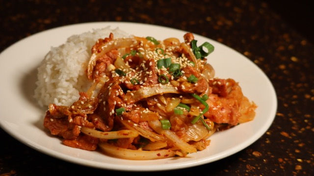 A savory stir-fry of sliced pork and onions topped with toasted sesame seeds and green onions at Good Friends