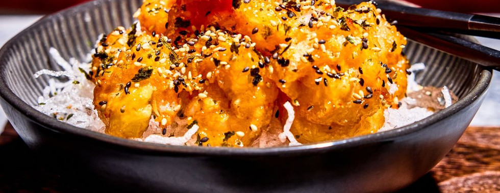 Crispy honey walnut rock shrimp garnished with black sesame seeds in a sleek black bowl at Resorts World Las Vegas.