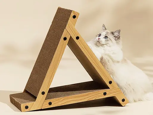 A ragdoll cat reaching up a wooden triangular scratcher with cardboard scratching faces.