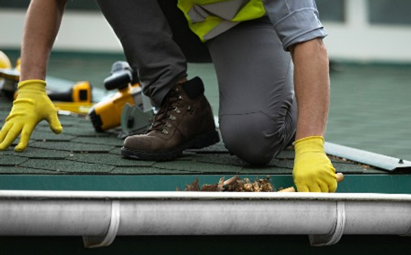 A man worker is cleaning a clogged roof
