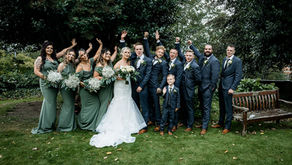 Bride and groom with bridesmaids and groomsmen posing outdoors in a garden on their wedding day.