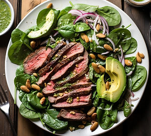 Spinach salad with grilled steak, pepitas (pumpkin seeds), and avocado-lime dressing