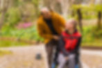 a person with a disability in the wheelchair being pushed by a friend in a public city par