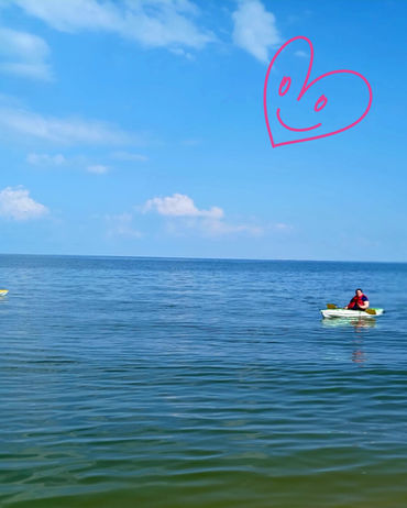 Retreat participants kayaking on the Chesapeake Bay during the August 2025 healing retreat in Scotland, Maryland with a red heart doodle in the sky