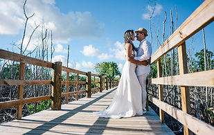 Pareja vestida de blanco mirandose a los ojos de forma romantica en el muelle del manglar de Playa Macao durante una sesion de fotos en pareja en Punta Cana Republica Dominicana