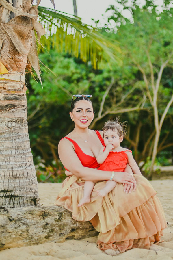Madre y bebe sentadas en un tronco de palmera rodeadas de naturaleza durante una sesion de fotos familiar en Macao Punta Cana
