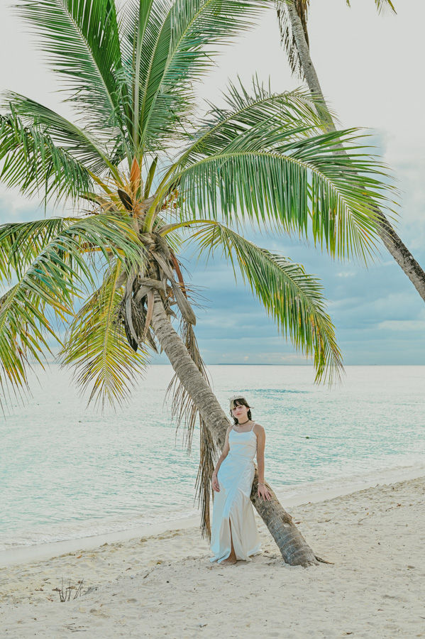 Retrato natural de quinceañera entre palmeras y arena blanca en Bayahibe.