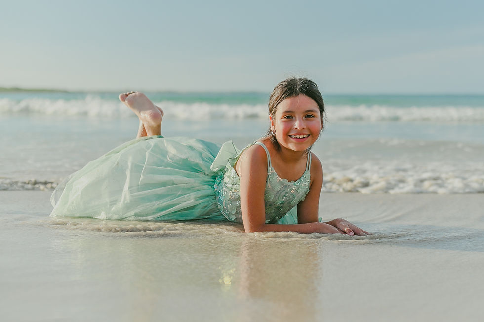 Birthday girl lying on the sand with her feet raised while looking at the camera during a children photoshoot at Macao Beach in Punta Cana Dominican Republic