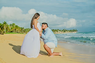 Futuro papá besando la barriga de su bebé durante una sesión de fotos de embarazo en Playa Uvero Alto, Punta Cana