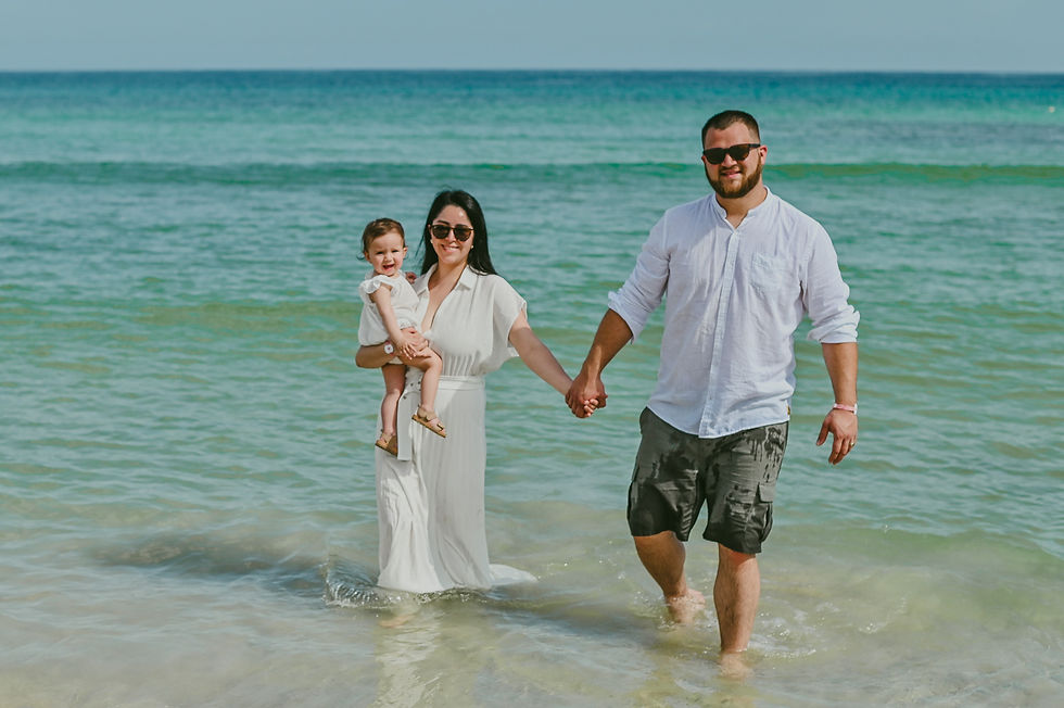 Padres tomados de la mano caminando por el agua de Playa Macao con su bebé en brazos de mamá.
