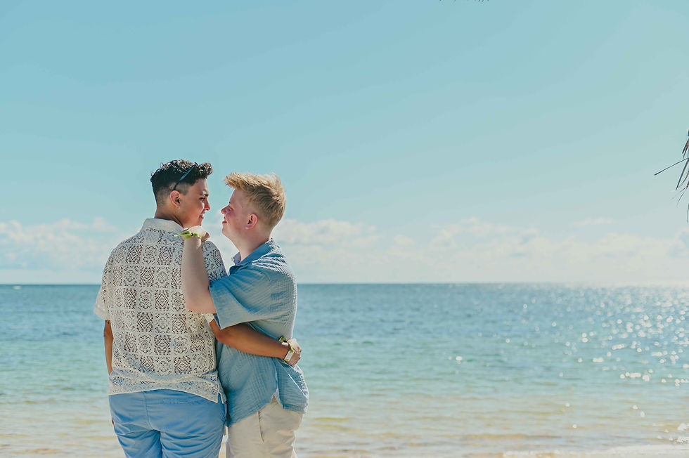Pareja LGBT de espaldas mirando el mar y abrazados, sesion romantica en la playa de Punta Cana Republica Dominicana.