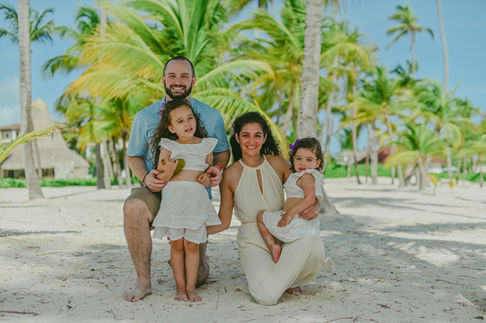Family of four posing with palm trees behind them in Punta Cana
