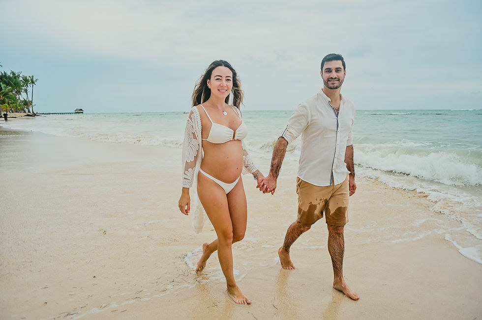 Paola y Enzo caminando por la playa durante su sesión de embarazo para anunciar la llegada de su bebé en Punta Cana.