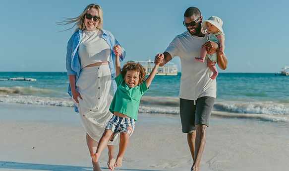 Family with a baby and young child walking by the ocean during a family photoshoot at Bávaro Beach in Punta Cana