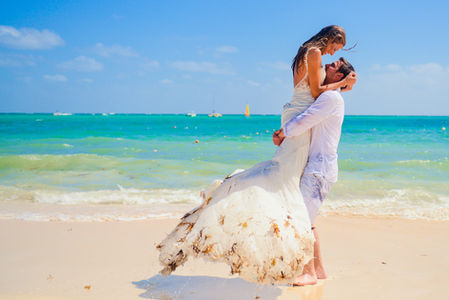 Novio levantando a la novia en brazos durante una sesión trash the dress en la playa de Punta Cana