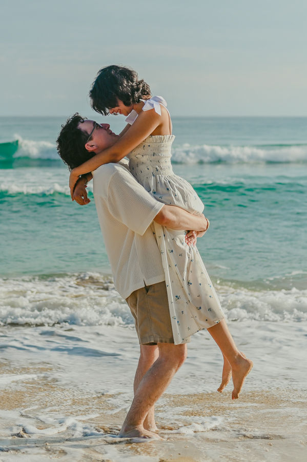Momento divertido levantandola en la orilla durante una sesion de fotos en pareja en Punta Cana en Republica Dominicana