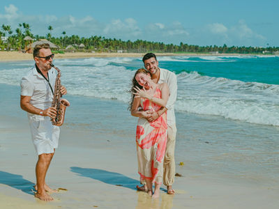 Surprise marriage proposal with a saxophonist on Uvero Alto Beach Punta Cana Dominican Republic, Diego and Javiera celebrating their engagement while Pascal Aubrion from Punta Cana Live Music plays live saxophone by the Caribbean Sea near Excellence Punta Cana
