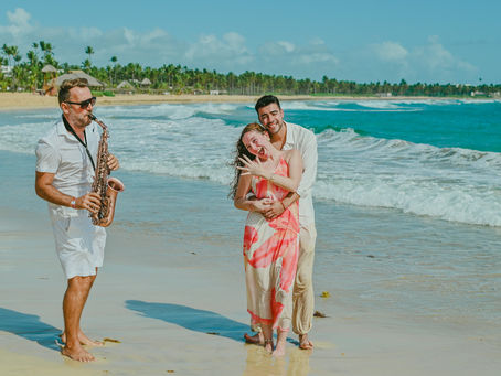Surprise marriage proposal with a saxophonist on Uvero Alto Beach Punta Cana Dominican Republic, Diego and Javiera celebrating their engagement while Pascal Aubrion from Punta Cana Live Music plays live saxophone by the Caribbean Sea near Excellence Punta Cana