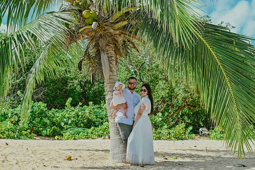 Padres con su bebé de un año bajo una palmera durante su sesión de fotos familiar en Playa Macao, Punta Cana.