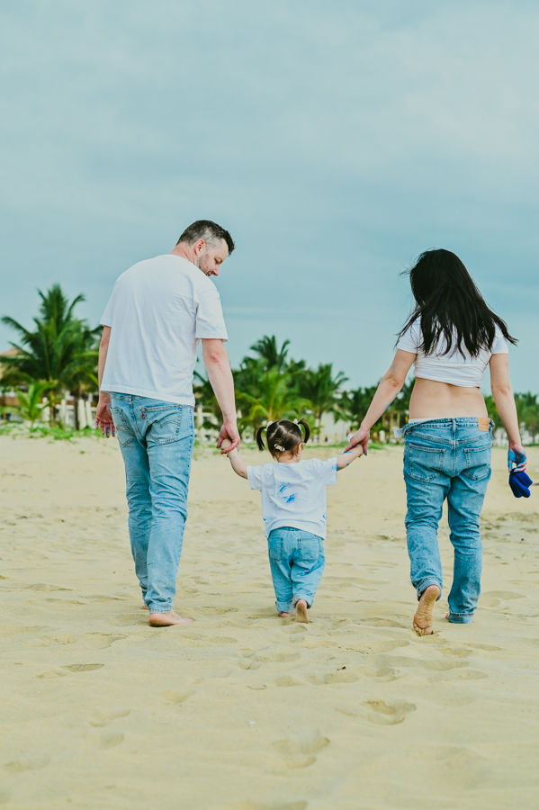 Familia caminando por la orilla al final de una sesión de embarazo y revelación de género en la playa de Miches.