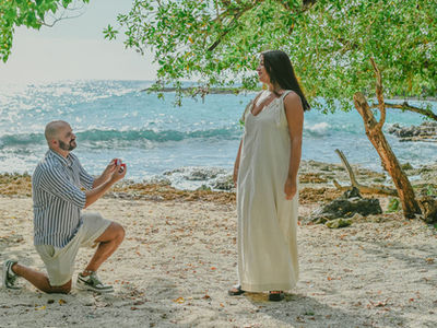 Surprise marriage proposal on a hidden beach in Bayahibe as José kneels with an engagement ring before Fiorella during a romantic photo session in the Dominican Republic.