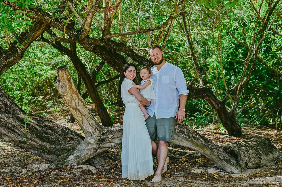 Familia con su bebé en brazos entre árboles y grandes raíces durante una sesión de fotos en Playa Macao.