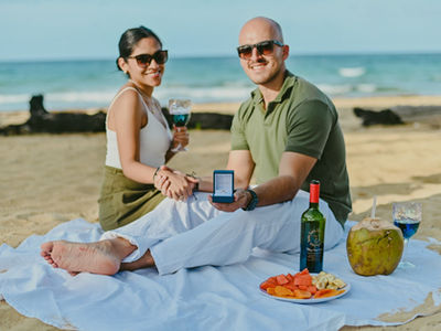 Surprise proposal in Punta Cana – picnic on the beach with engagement ring presented to the camera by the couple