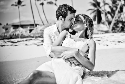 Pareja de reciƩn casados en blanco y negro, ella recostada en los brazos del novio y mirƔndose con ternura en la playa de Punta Cana