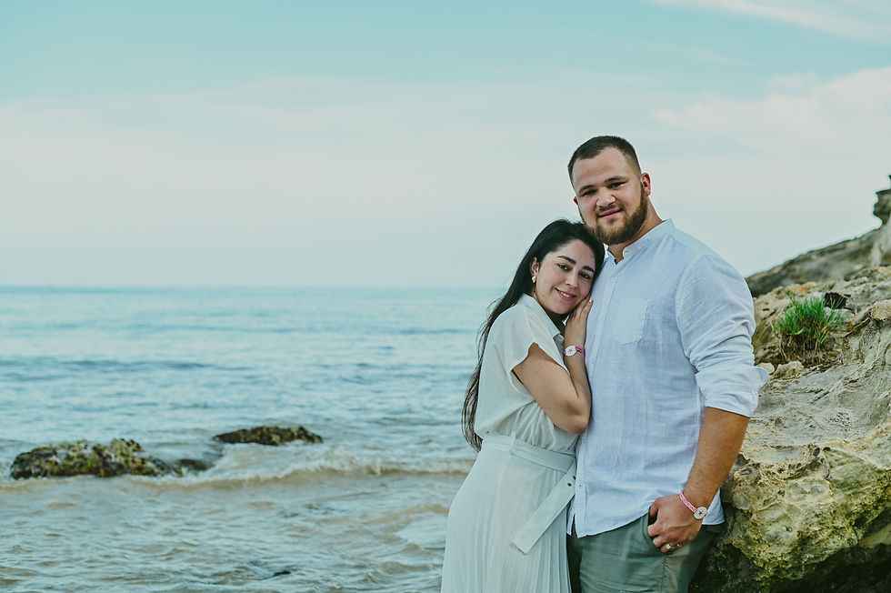 Retrato cercano de los padres con su bebé entre ambos junto a las rocas de Playa Macao.