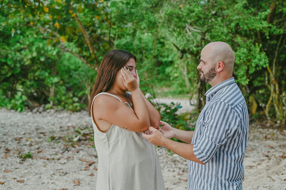 Hombre pidiendo matrimonio a su pareja en una playa de Bayahibe mientras ella descubre emocionada el anillo durante una propuesta de matrimonio sorpresa.