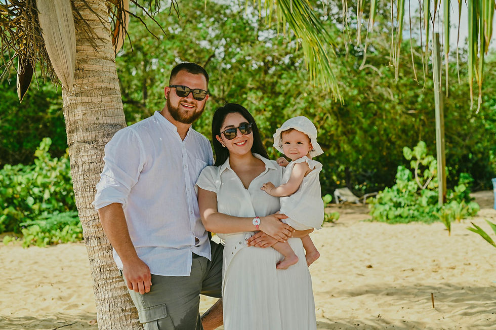 Padres con su bebé usando sombrero y lentes de sol junto a las palmeras de Playa Macao.
