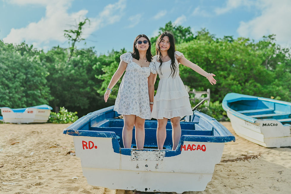 Dos hermanas de pie sobre un barco de pescadores durante una sesion de fotos familiar de graduacion en Playa Macao Punta Cana Republica Dominicana con fotografo profesional