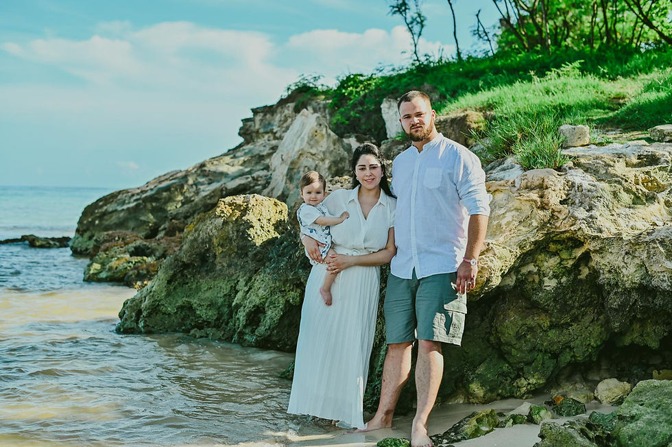 Familia con su bebé en brazos junto a las rocas y el mar de Playa Macao durante sus vacaciones en Punta Cana.