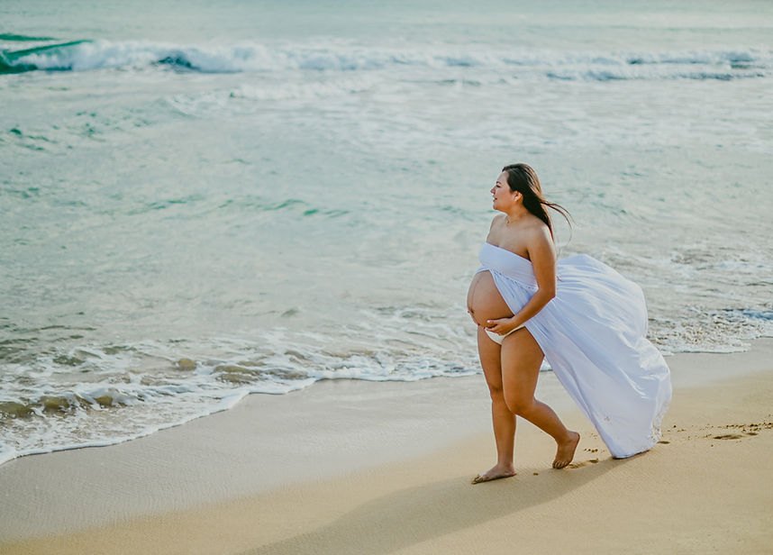 Pregnant woman walking by the ocean during a maternity photoshoot in Uvero Alto, Punta Cana, near Excellence El Carmen.