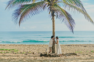 Pareja disfrutando de una sesión de fotos romántica bajo una palmera en Playa Uvero Alto, Punta Cana