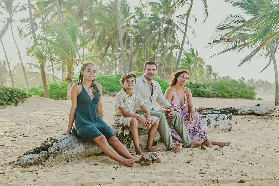 Family gathered on a driftwood log during a sunset anniversary photoshoot on Uvero Alto Beach